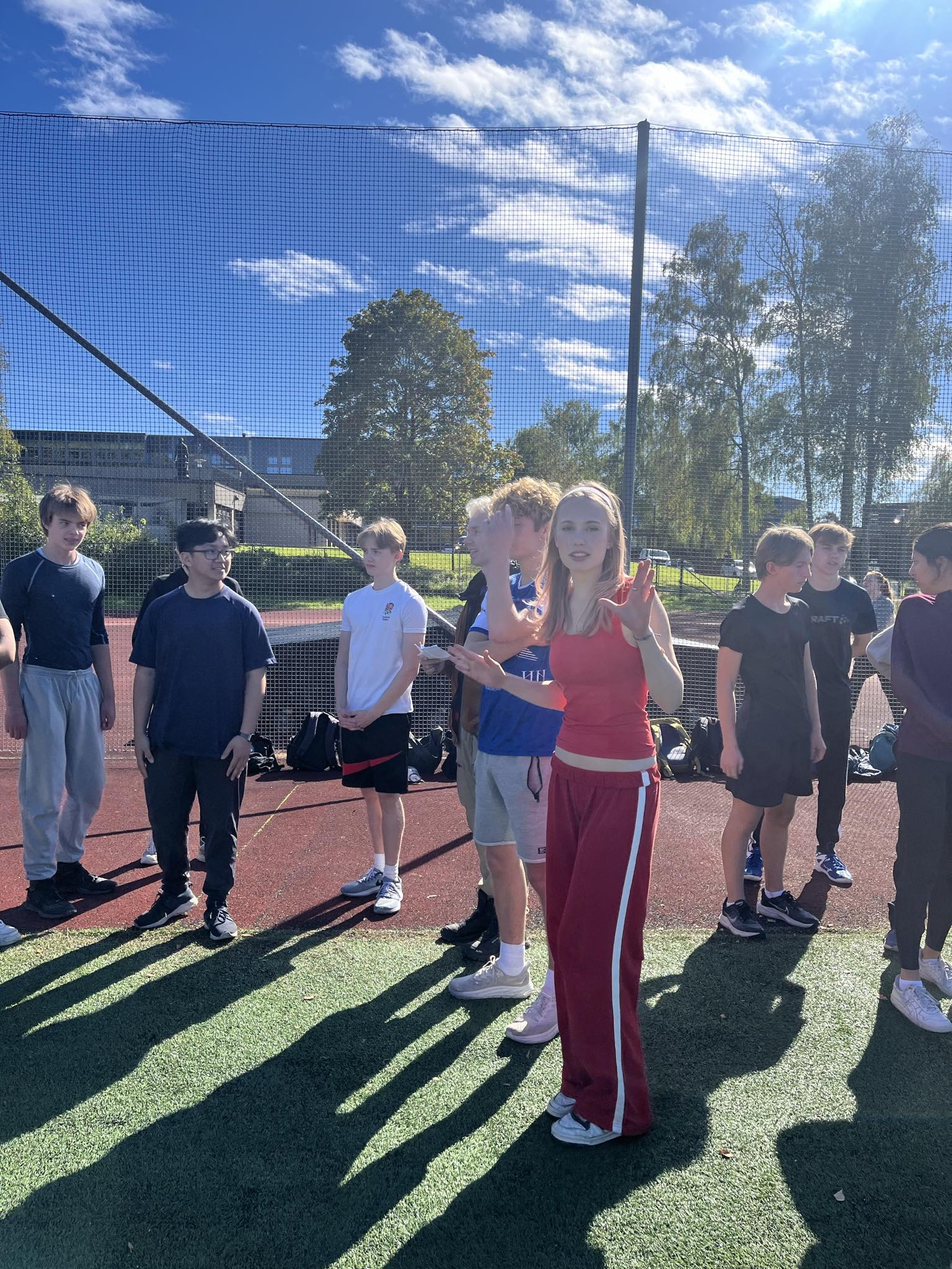 en gruppe mennesker som står på et jorde med et gjerde og et fjell i bakgrunnen