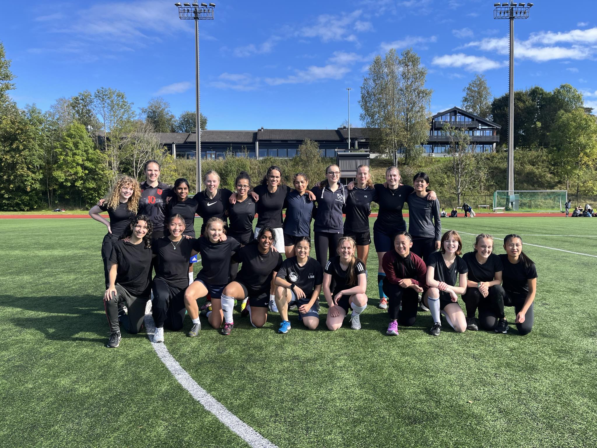 En gruppe mennesker som poserer for et bilde på en fotballbane