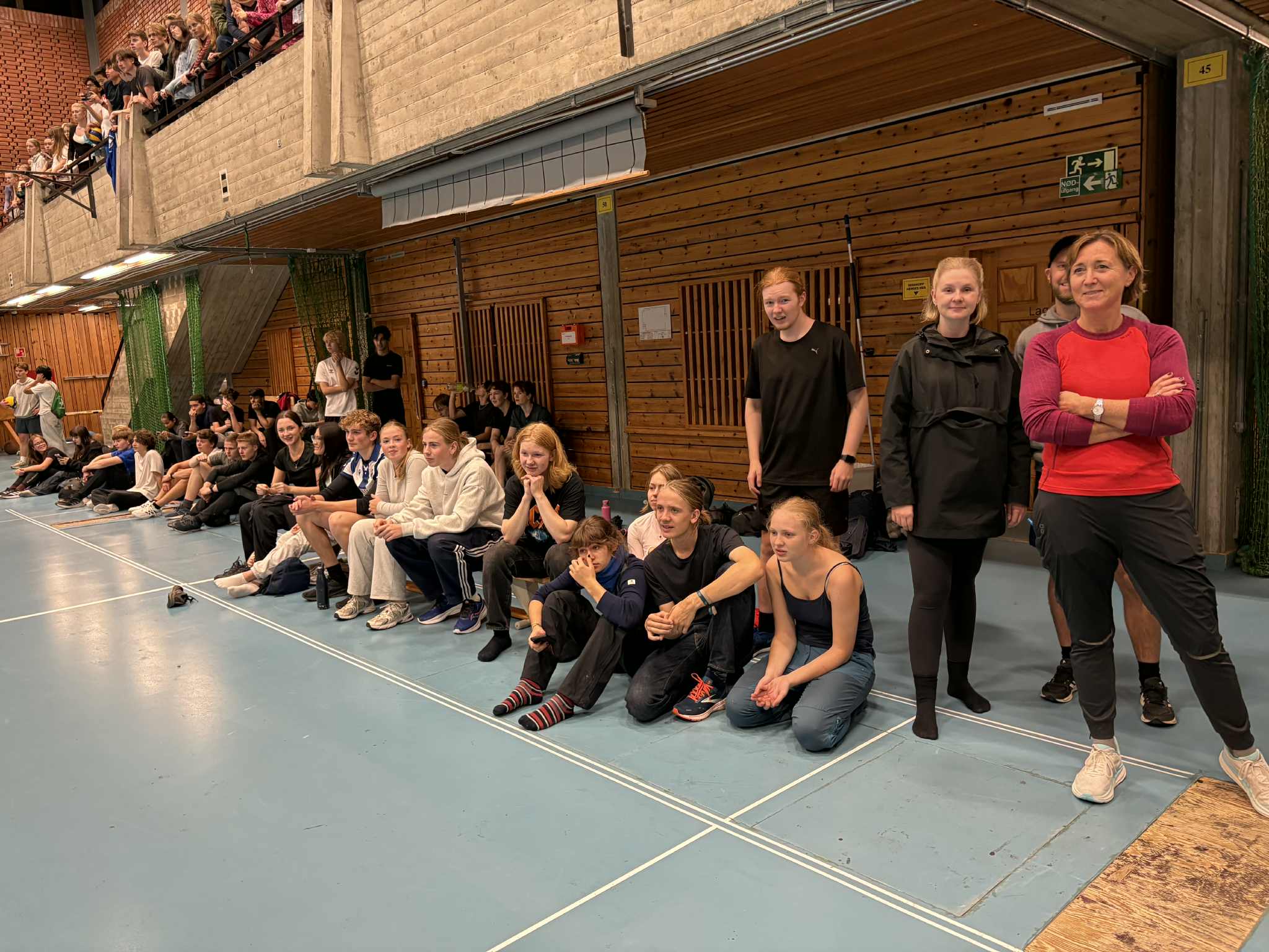 en gruppe mennesker som sitter på en blå matte foran en murbygning