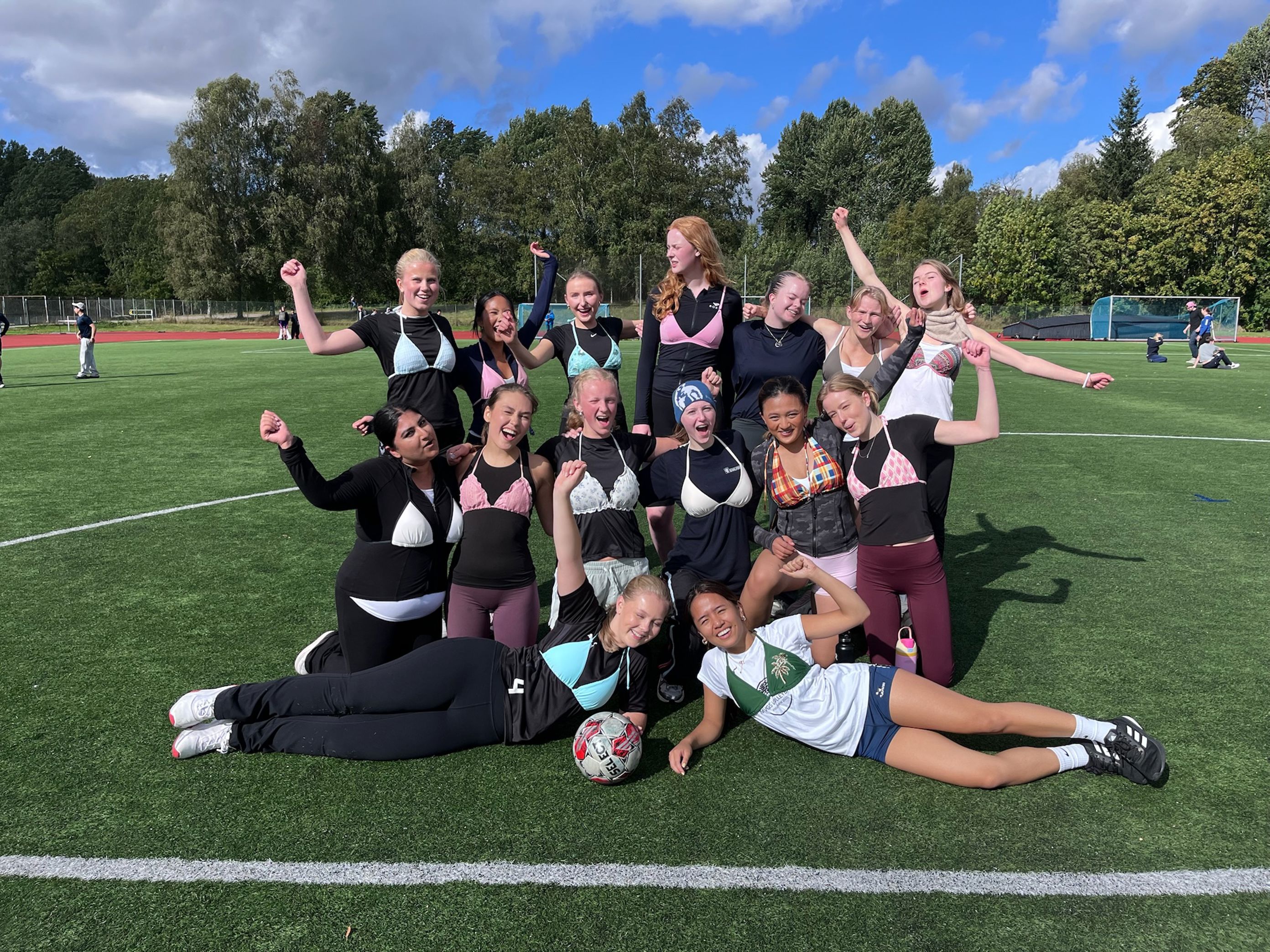 en gruppe mennesker som poserer for et bilde på en fotballbane