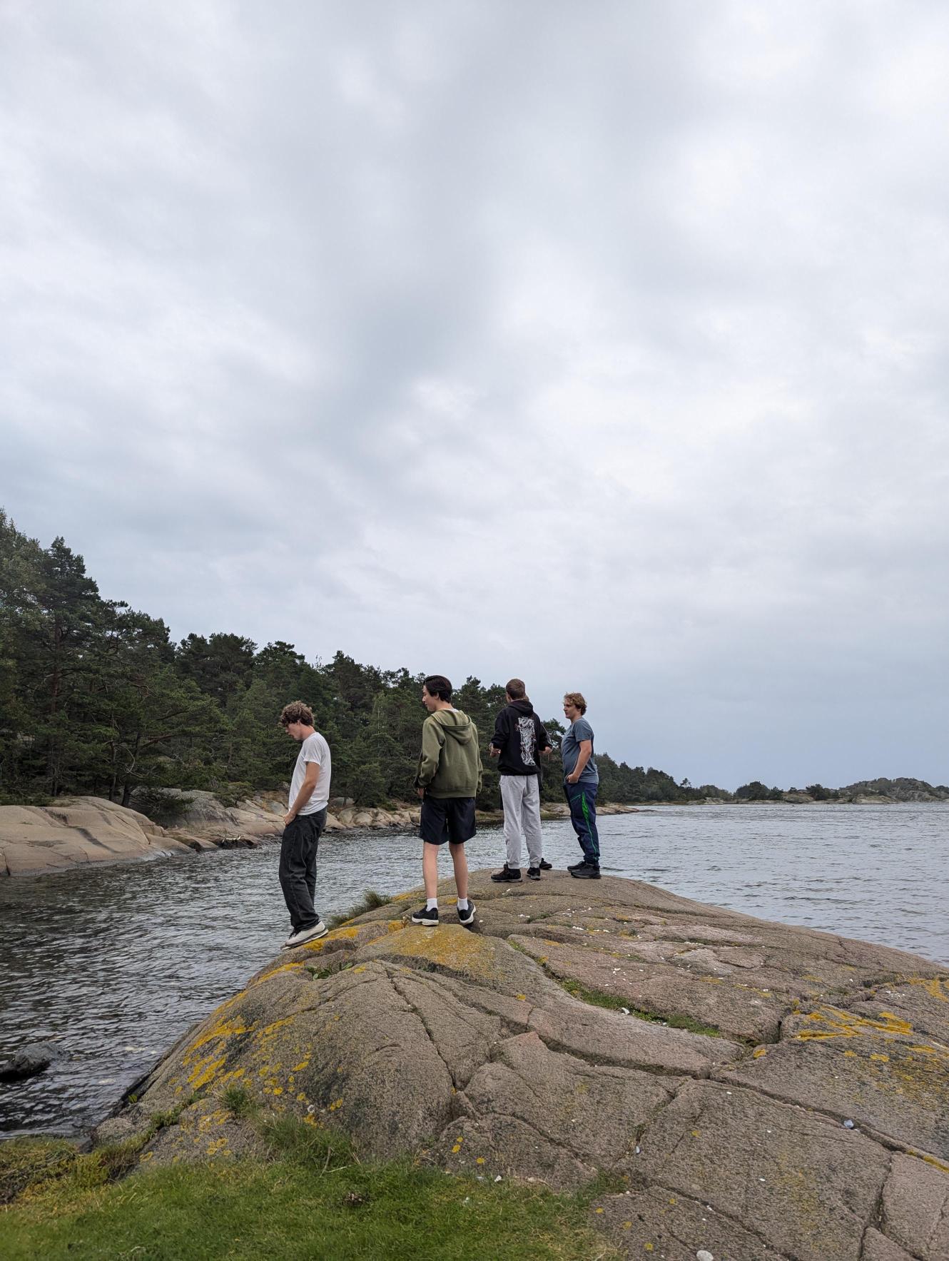 en gruppe mennesker som står på en stein ved en vannmasse