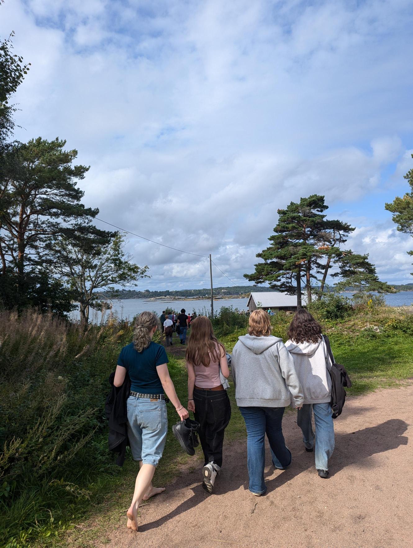 en gruppe mennesker som går på en sti nær en vannmasse