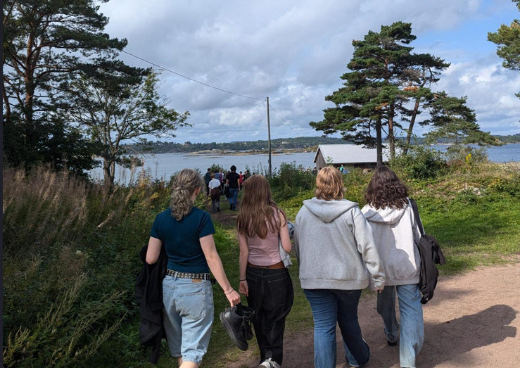 en gruppe mennesker som går på en sti nær en vannmasse
