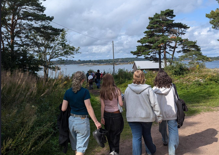 en gruppe mennesker som går på en sti nær en vannmasse