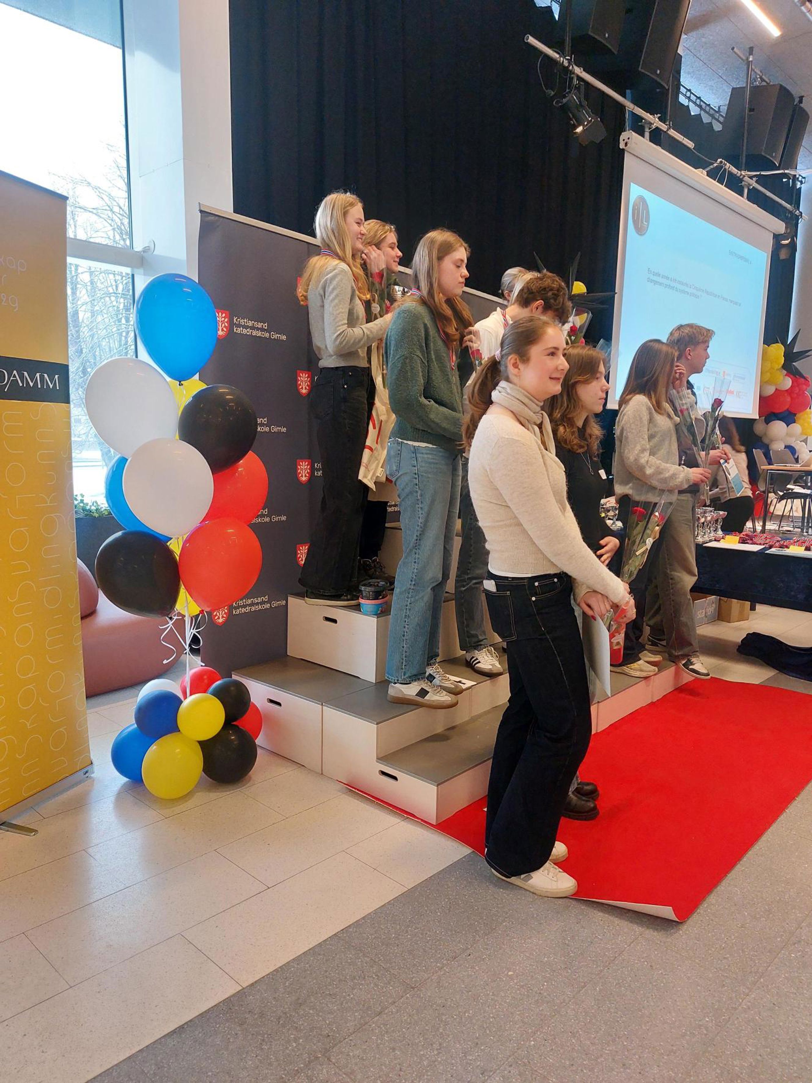 En gruppe mennesker som står på en rød løper med ballonger