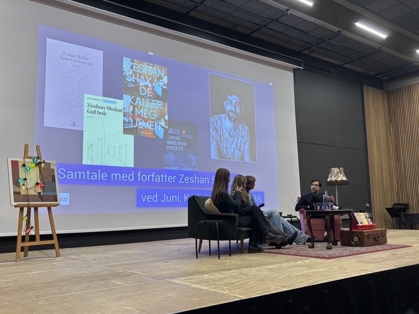 En gruppe mennesker som sitter foran en stor skjerm