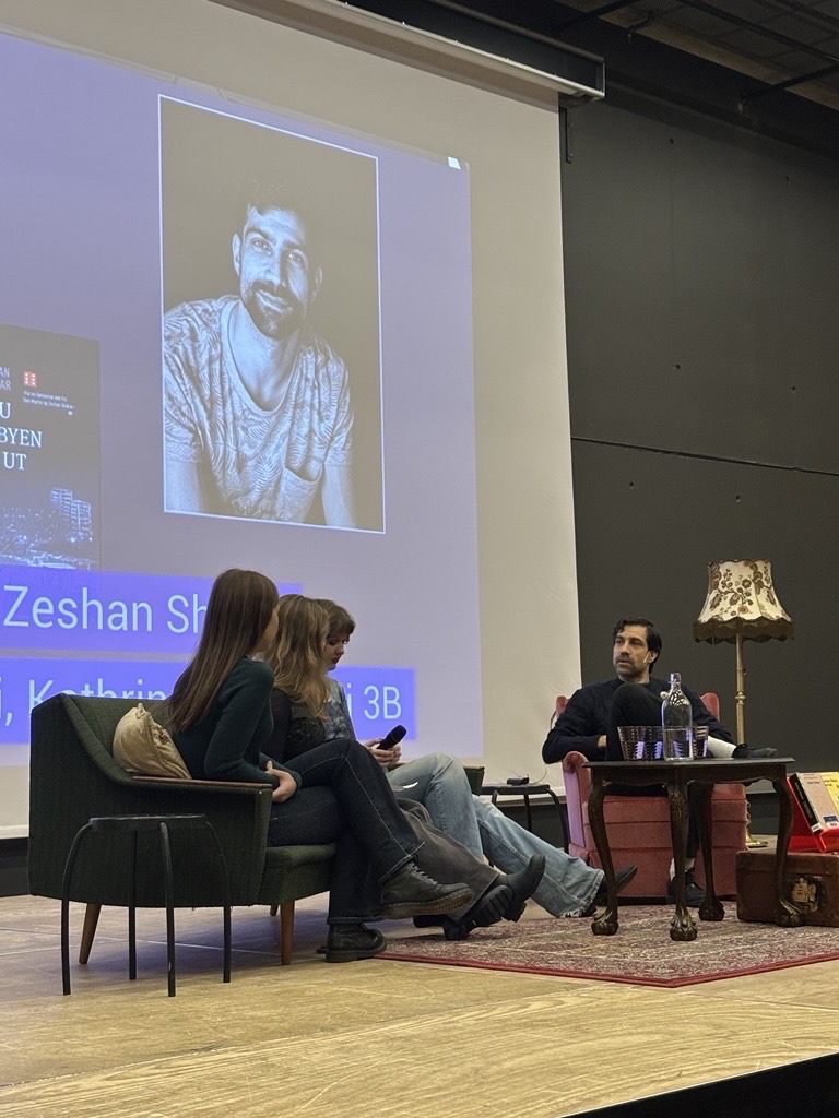 en gruppe mennesker som sitter i stoler foran en projektorskjerm