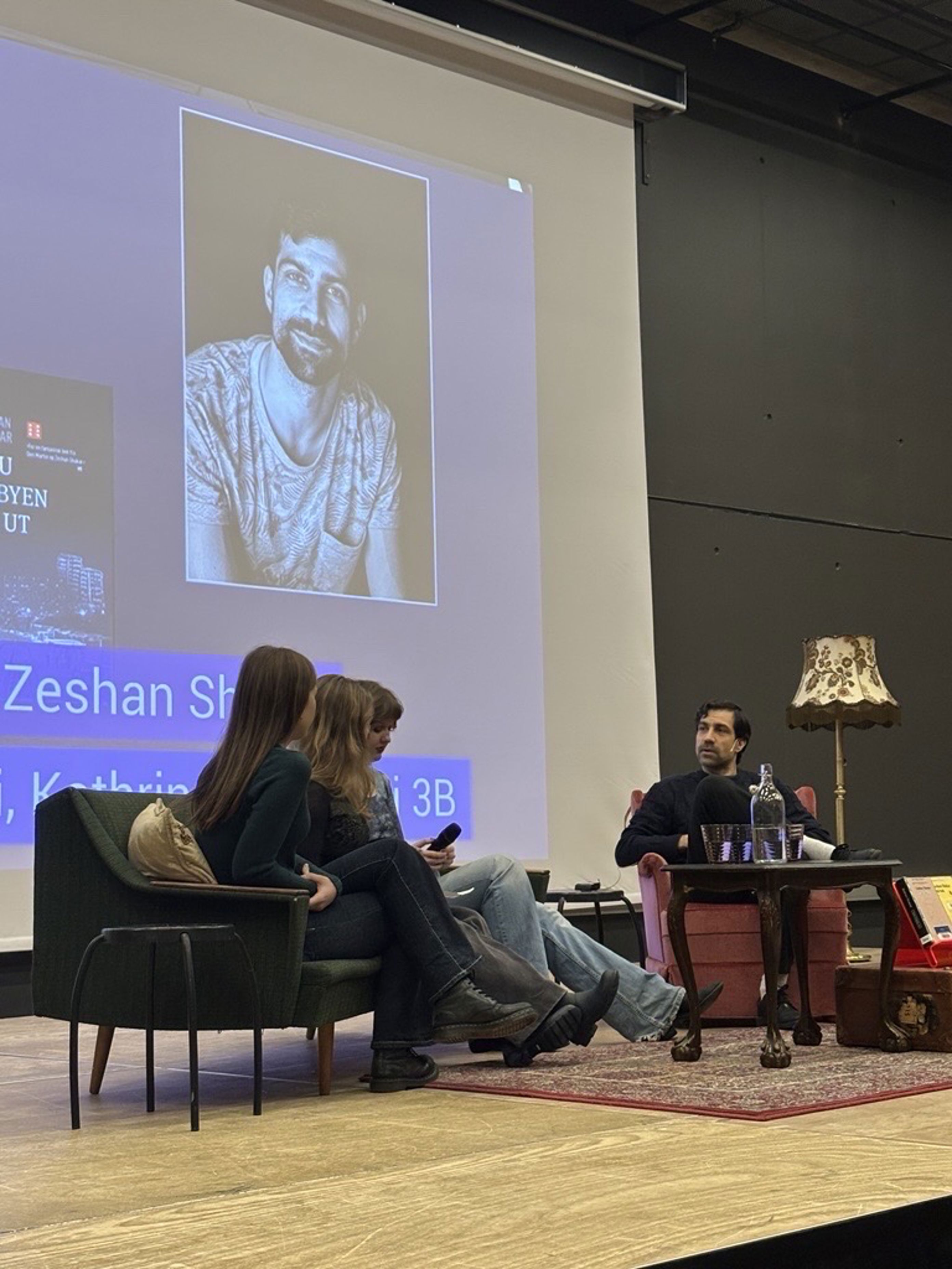 en gruppe mennesker som sitter i stoler foran en projektorskjerm