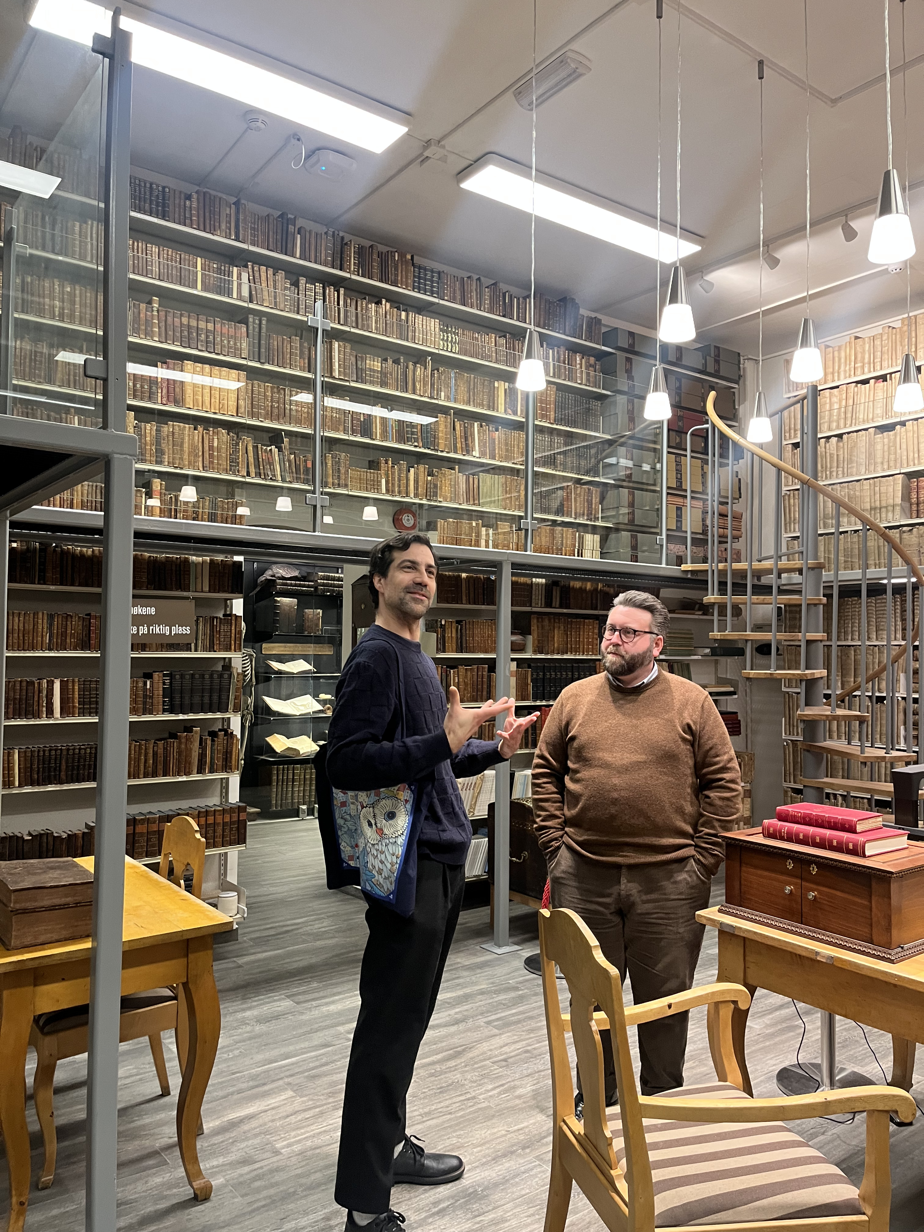 En person og en person som står i et rom med bokhyller