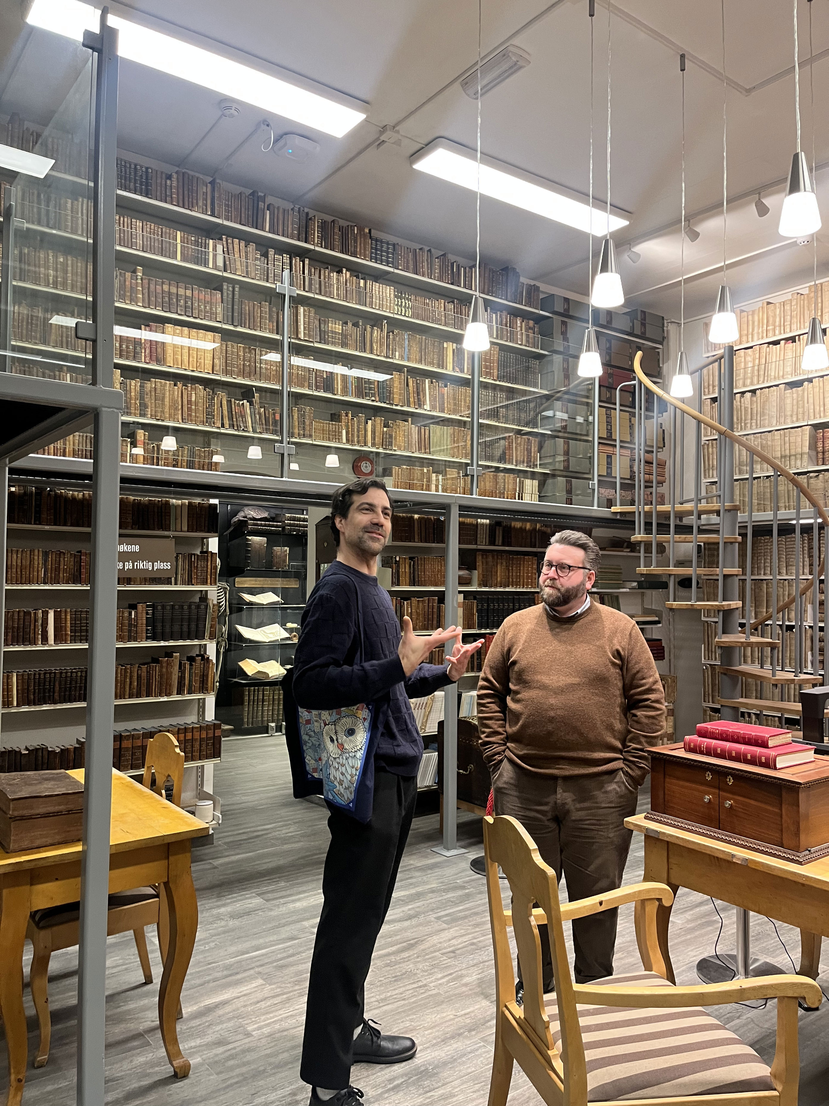 En person og en person som står i et rom med bokhyller