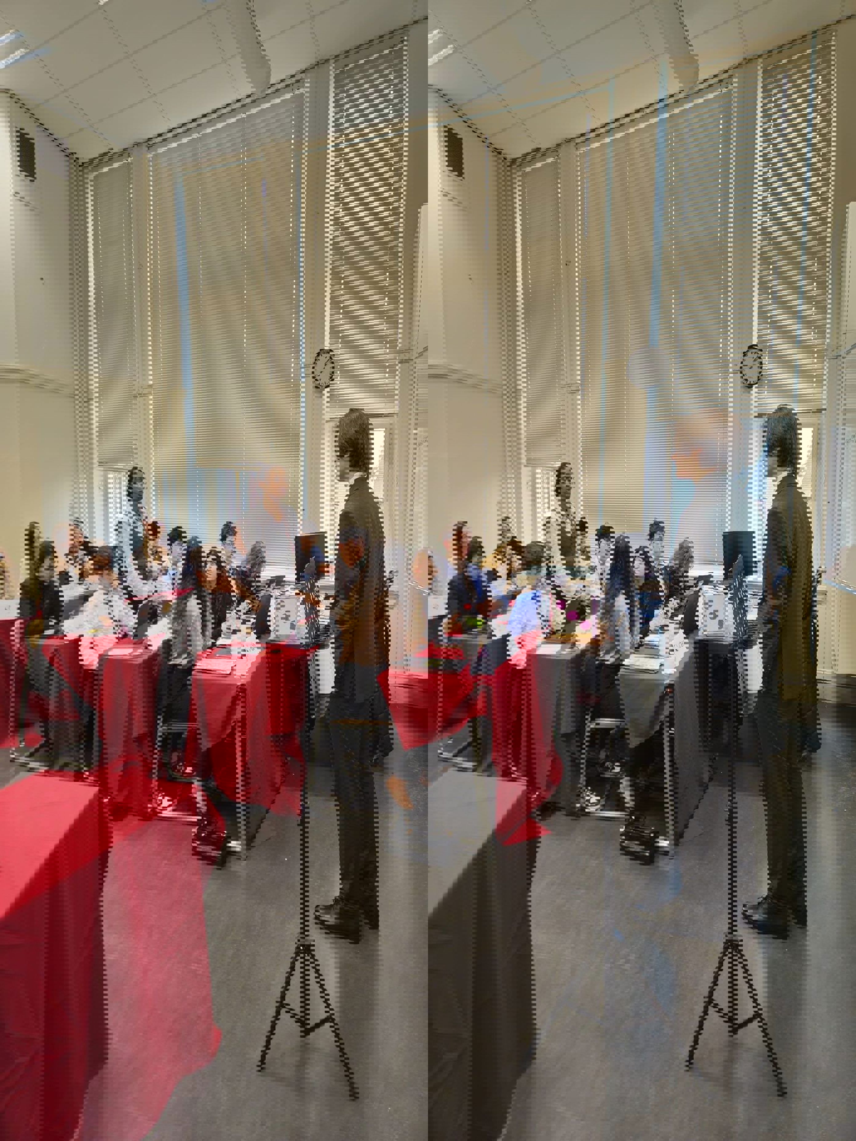 Foto: Julia Kagge en person som står foran en gruppe mennesker som sitter ved bord