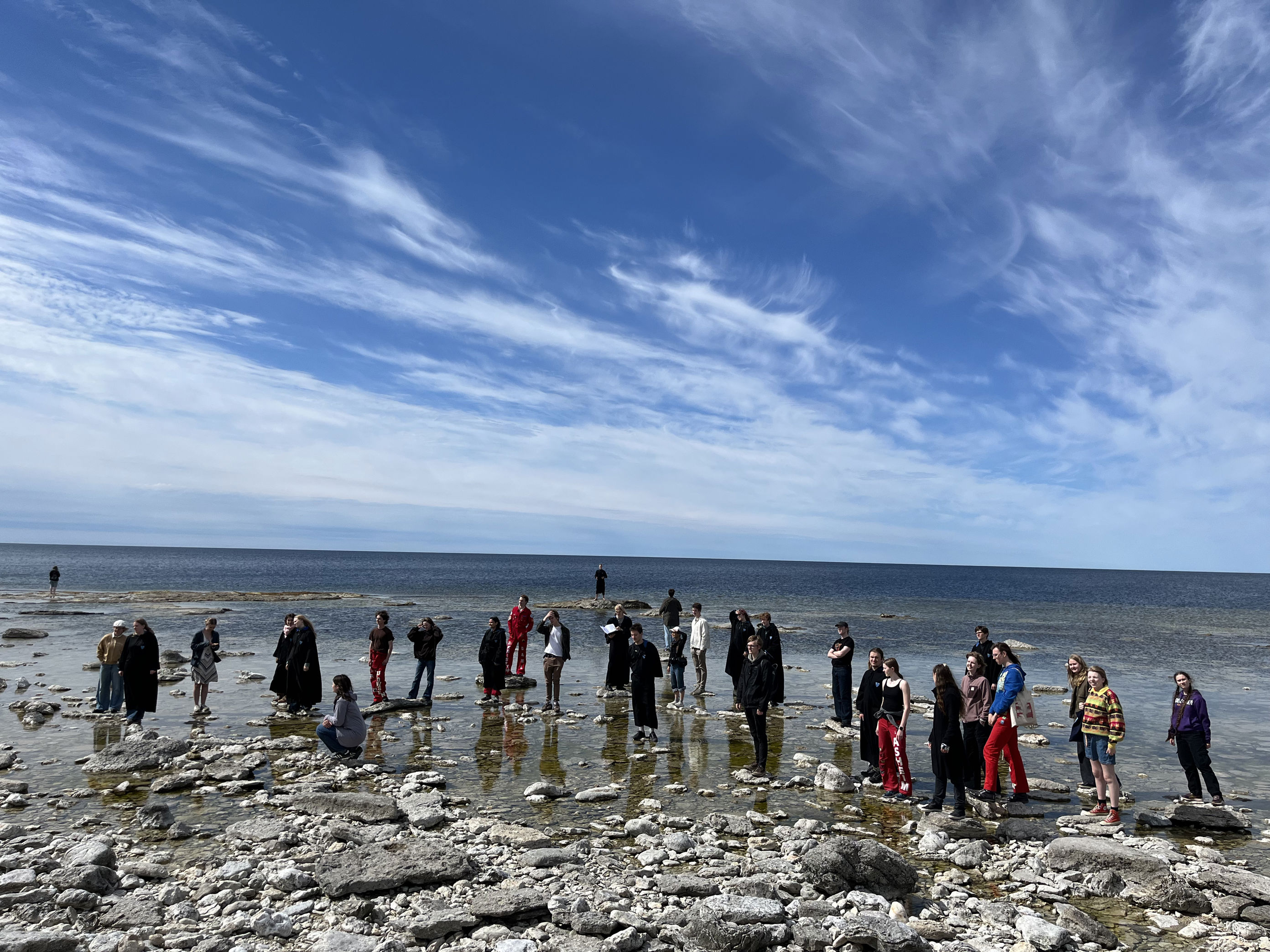En gruppe mennesker som står på en steinete strand