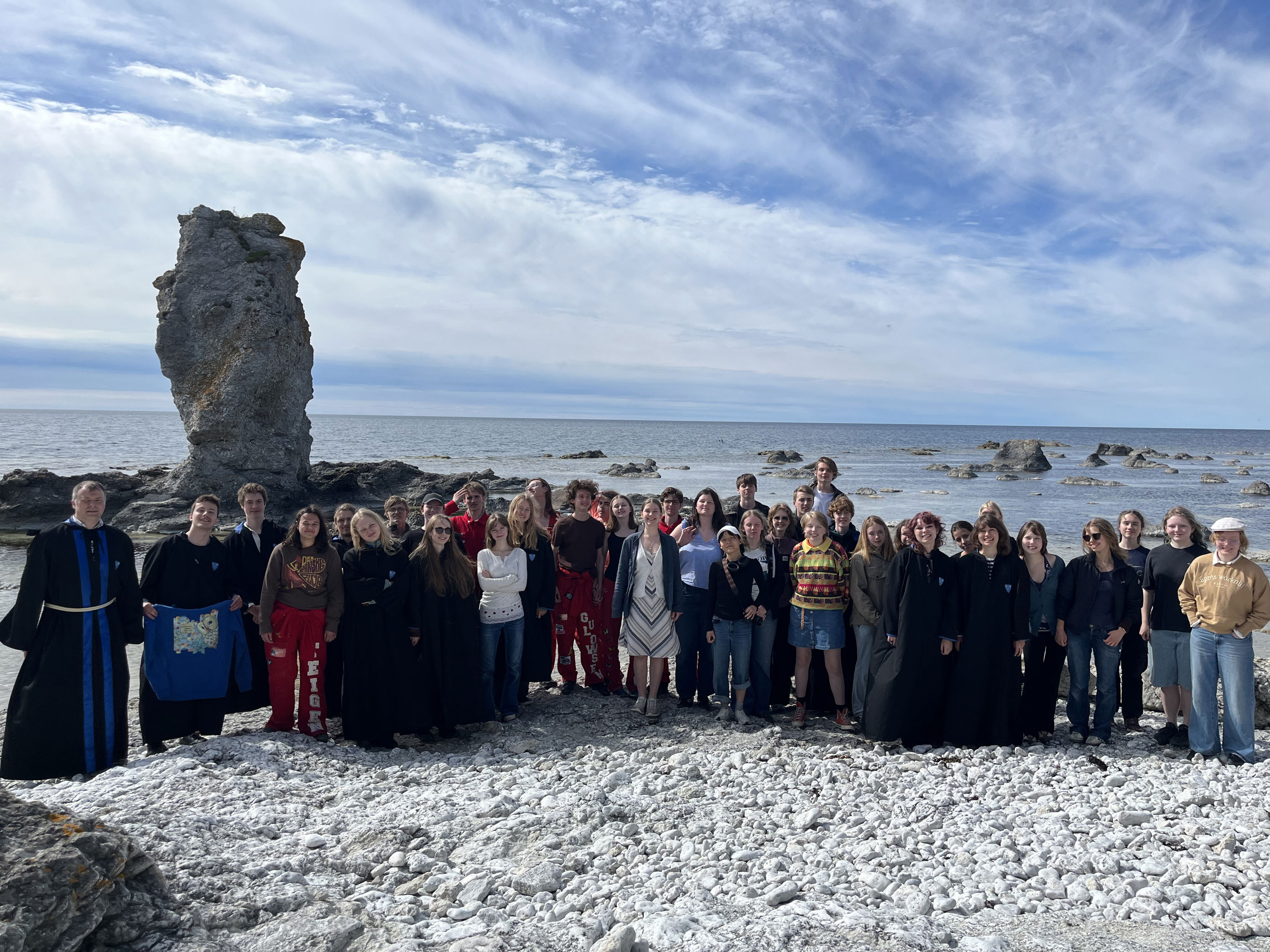 En gruppe mennesker poserer for et bilde på en steinete strand