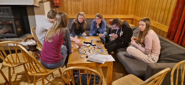 en gruppe mennesker som sitter rundt et bord og spiller et brettspill