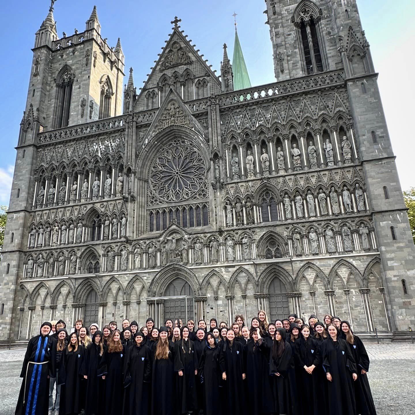 en gruppe mennesker foran et stort bygg med Nidarosdomen i bakgrunnen