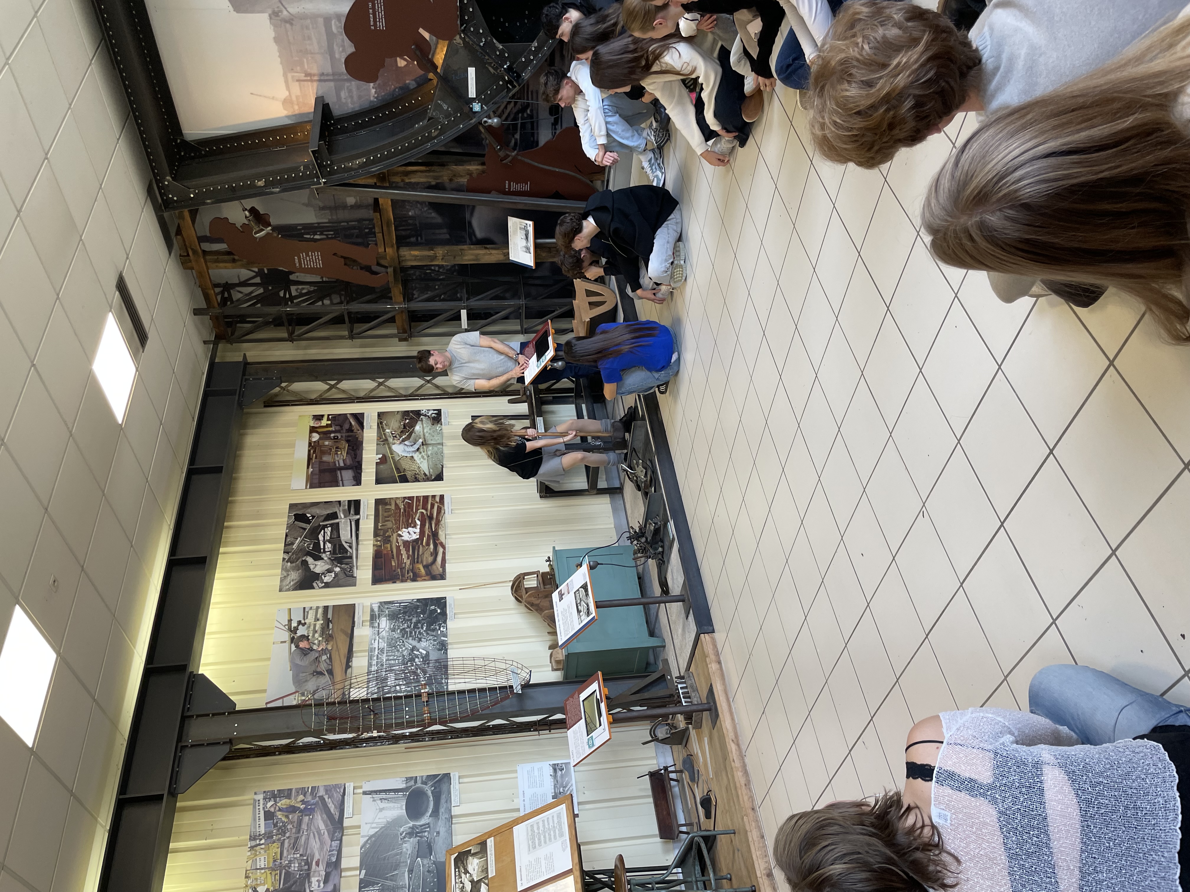 en gruppe mennesker som sitter i et rom med en person som spiller gitar