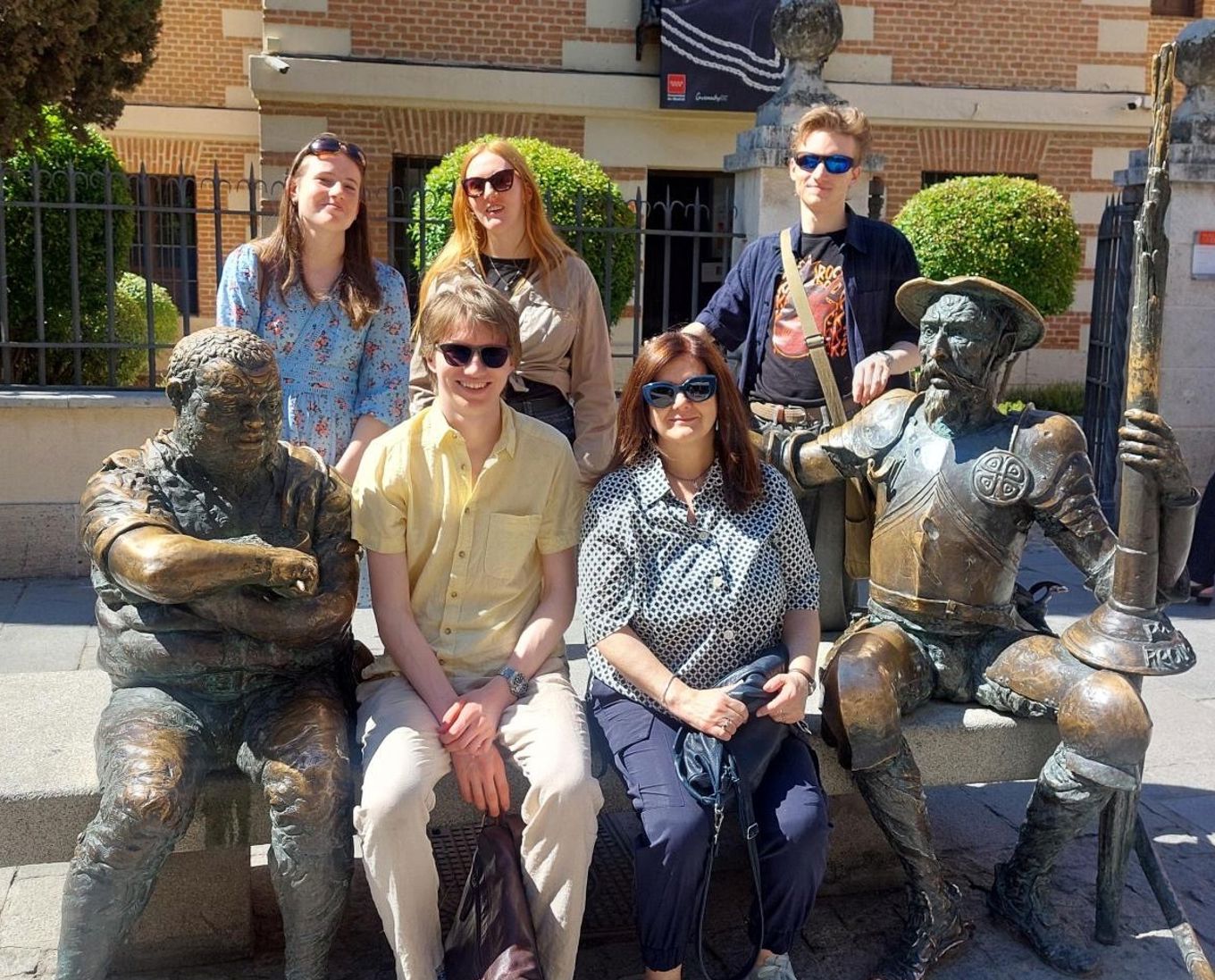 en gruppe mennesker poserer for et bilde foran en statue