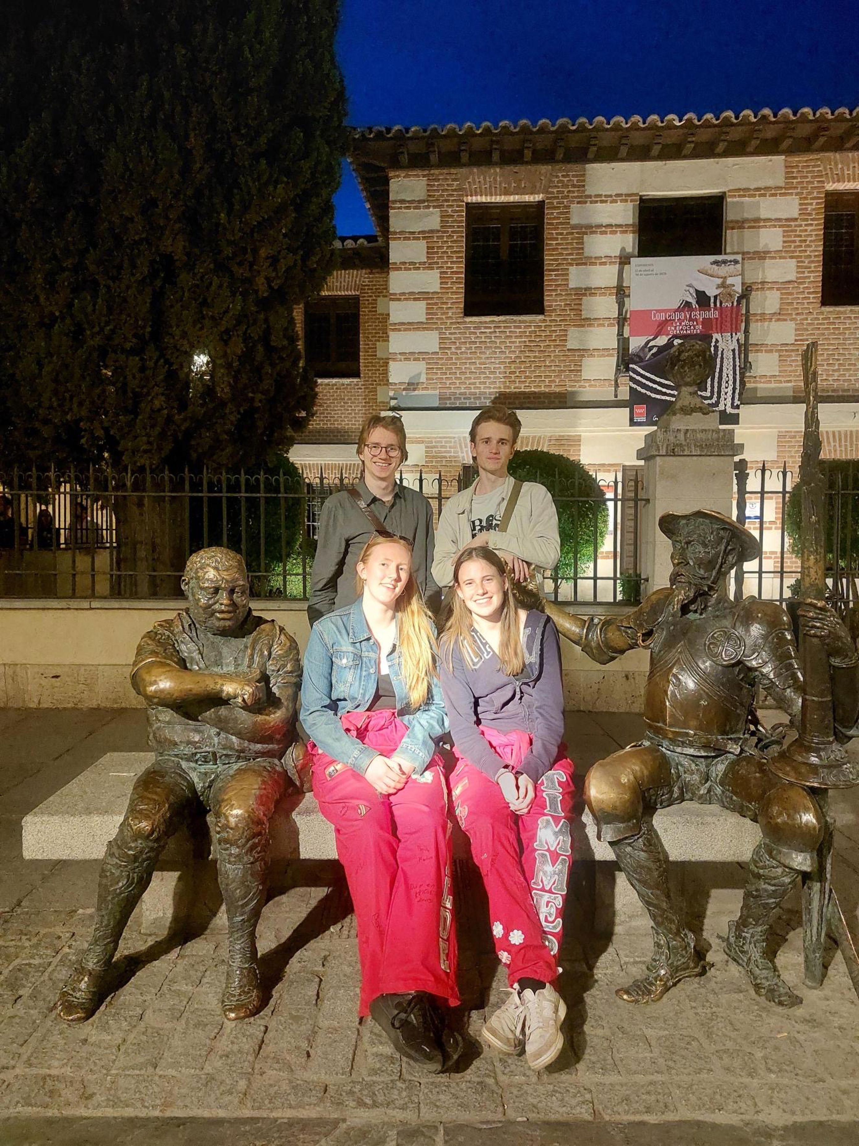 en gruppe mennesker poserer for et bilde foran en statue