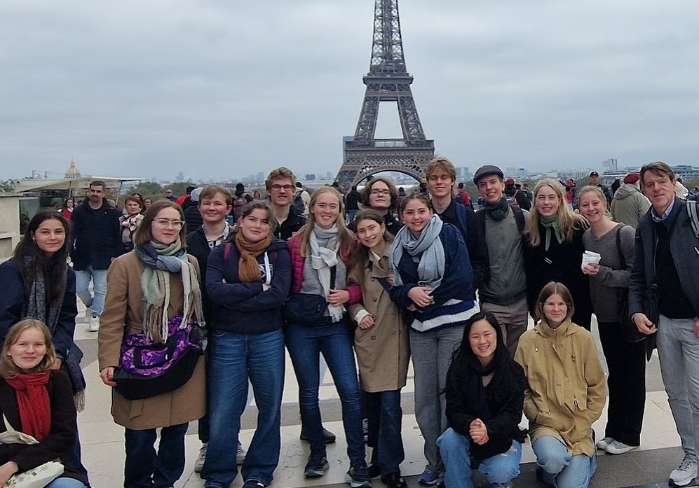 en gruppe mennesker som poserer for et bilde foran et høyt tårn