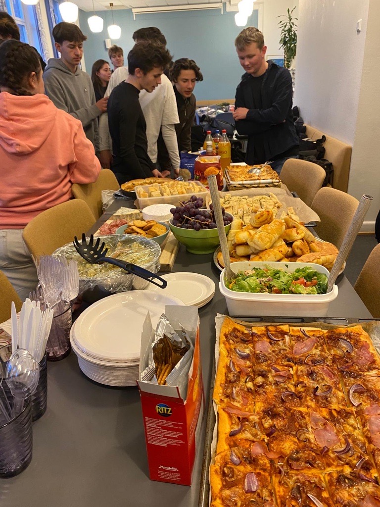 en gruppe mennesker som står rundt et bord fullt av mat